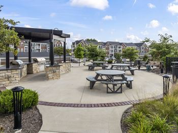 A park with picnic tables and a building in the background.